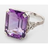 AN 18CT WHITE GOLD AND AMETHYST RING, centre claw-set emerald cut amethyst, the shoulder with leaf