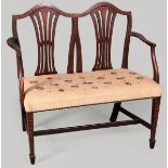 AN EDWARDIAN MAHOGANY SHERATON REVIVAL SMALL SETTEE, the double shield back with wheat-sheaf