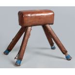 A VINTAGE GYMNASTICS HORSE, the heavily padded leather bolster supported by four leather covered
