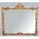 A ROCOCO-STYLE GILT FRAMED MIRROR, the rectangular plate framed with scrolling foliage with a