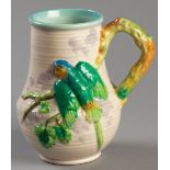 A CLARICE CLIFF JUG, with fold-over rim, branch-form handle, the body decorated with a budgie in
