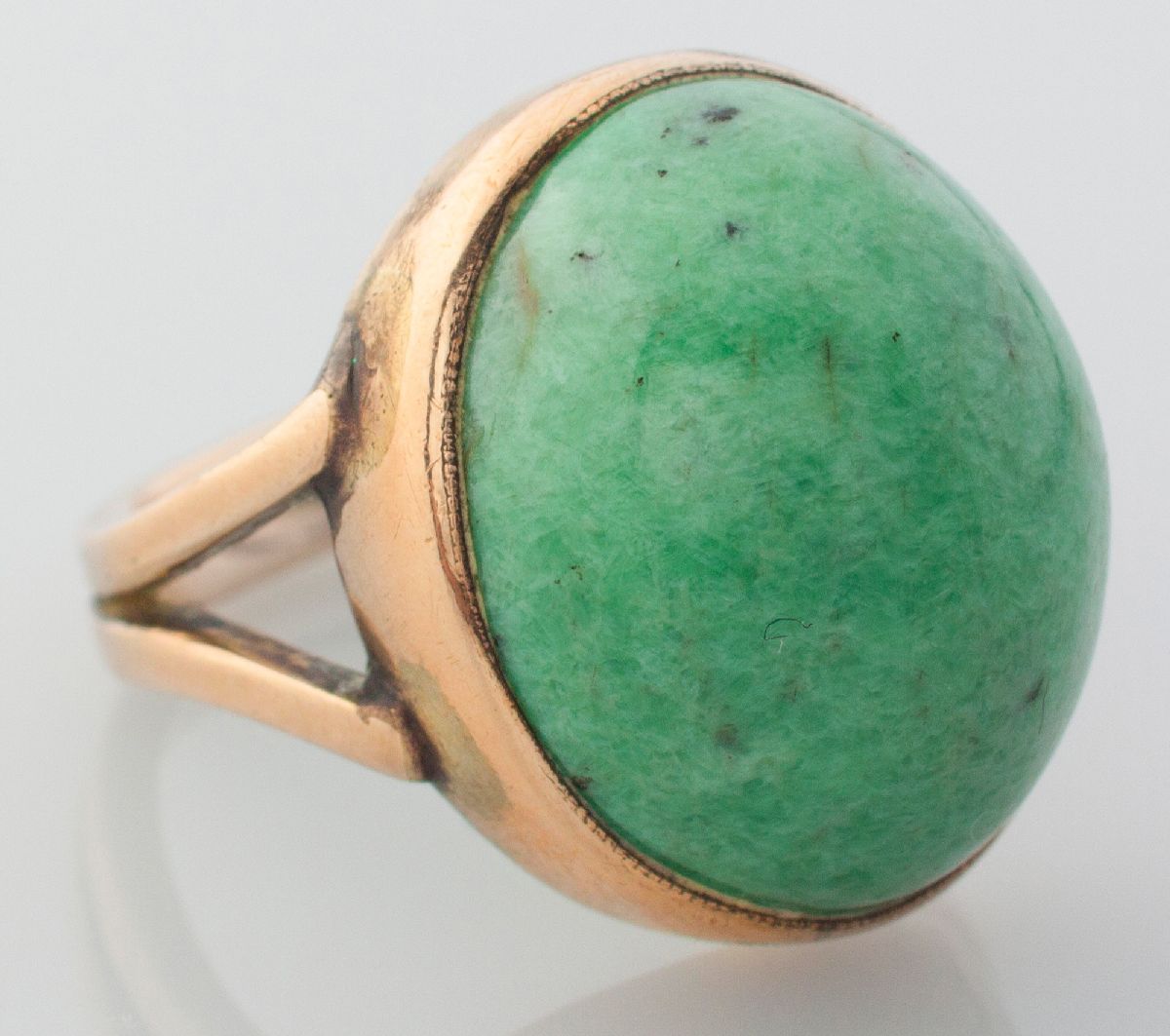 A 9CT YELLOW GOLD AND CABOCHON AVENTURINE RING, the dome shape stone in tube-setting, split