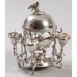 A SILVERPLATE EGG CODDLER, the removable top with eagle-form finial, shell embossed border with twin