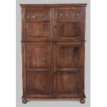 A 20TH CENTURY OAK CUPBOARD, the restrained pediment above two cupboard doors, decorated with carved