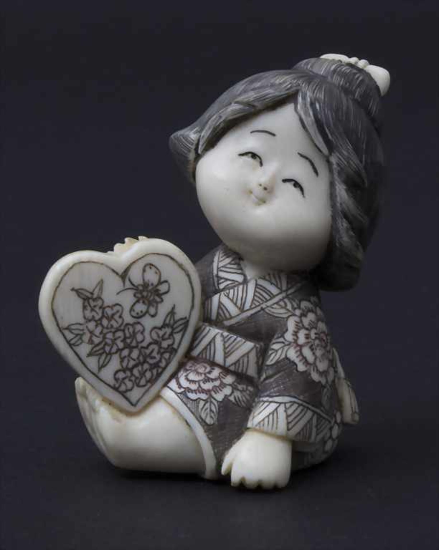 Netsuke 'Mädchen mit Herz' / A Netsuke 'girl with a heart', Japan, um 1900Material: Elfenbein,
