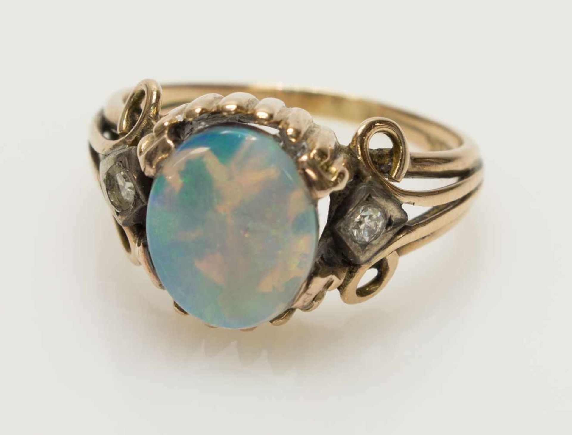 Damenring585er GG, 4,3 g, Ringschiene im Verlauf, ovaler Ringkopf mit einem Opal im Zentrum, umgeben