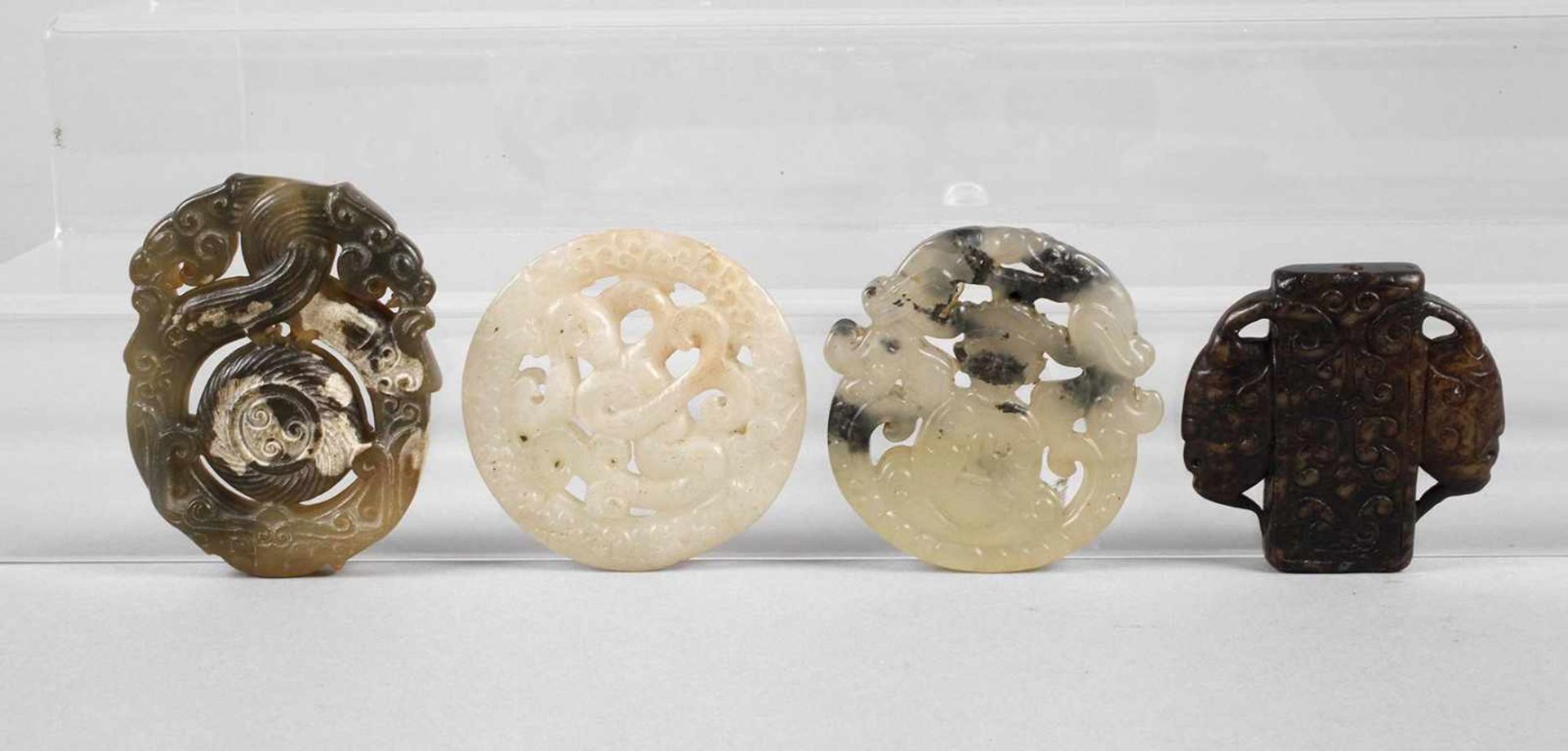 Vier JadeschnitzereienChina, 20. Jh., verschiedenfarbige Nephrite/Jadeite, aufwendig durchbrochen