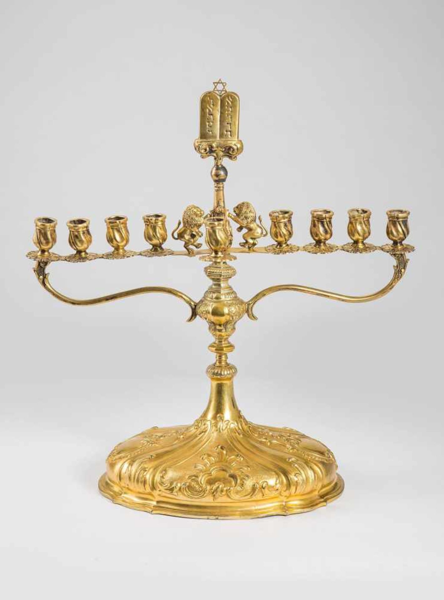 Chanukka-Leuchterin barocker Form. Metall vergoldet, auf ovalem barocken Unterteil der Aufsatz für 9
