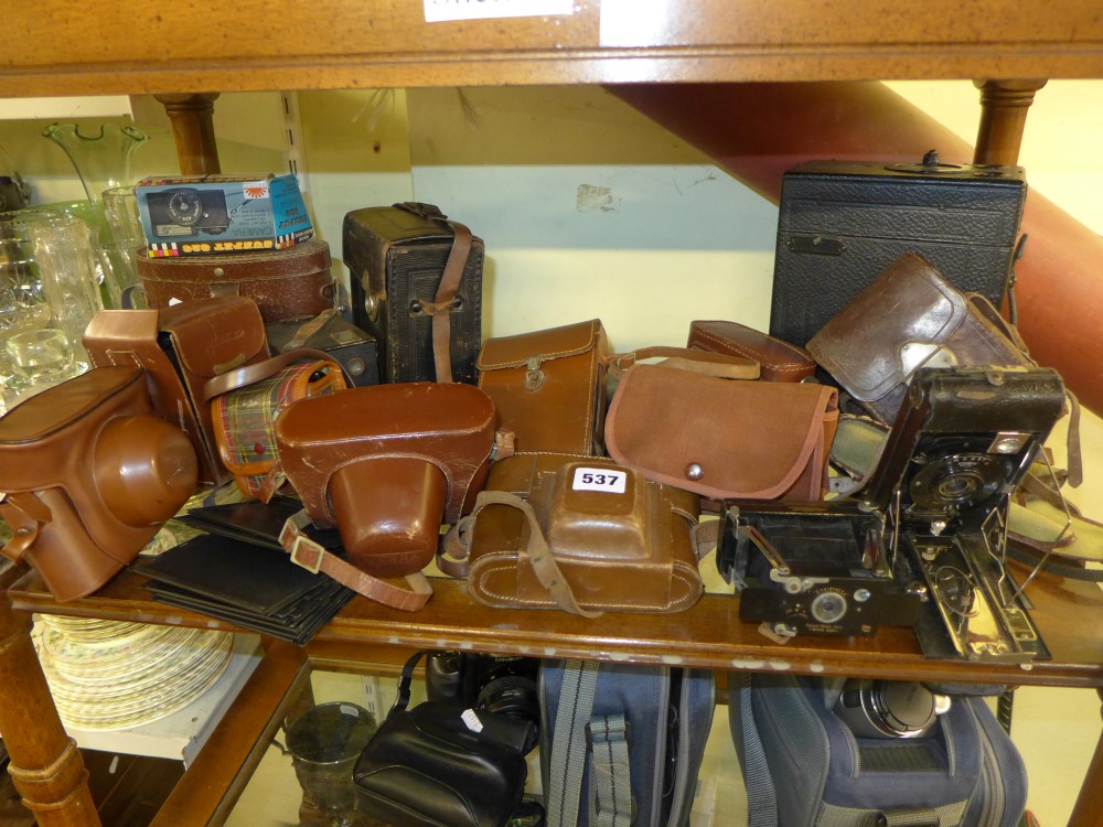 A shelf of cameras including an Ilford Advocate white camera, a cased Werra 3 in olive green, a