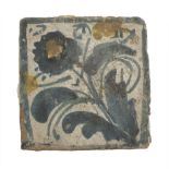 SMALL MAIOLICA TILE, CENTRAL ITALY 17TH CENTURY in white and blue enamel decorated with flower.