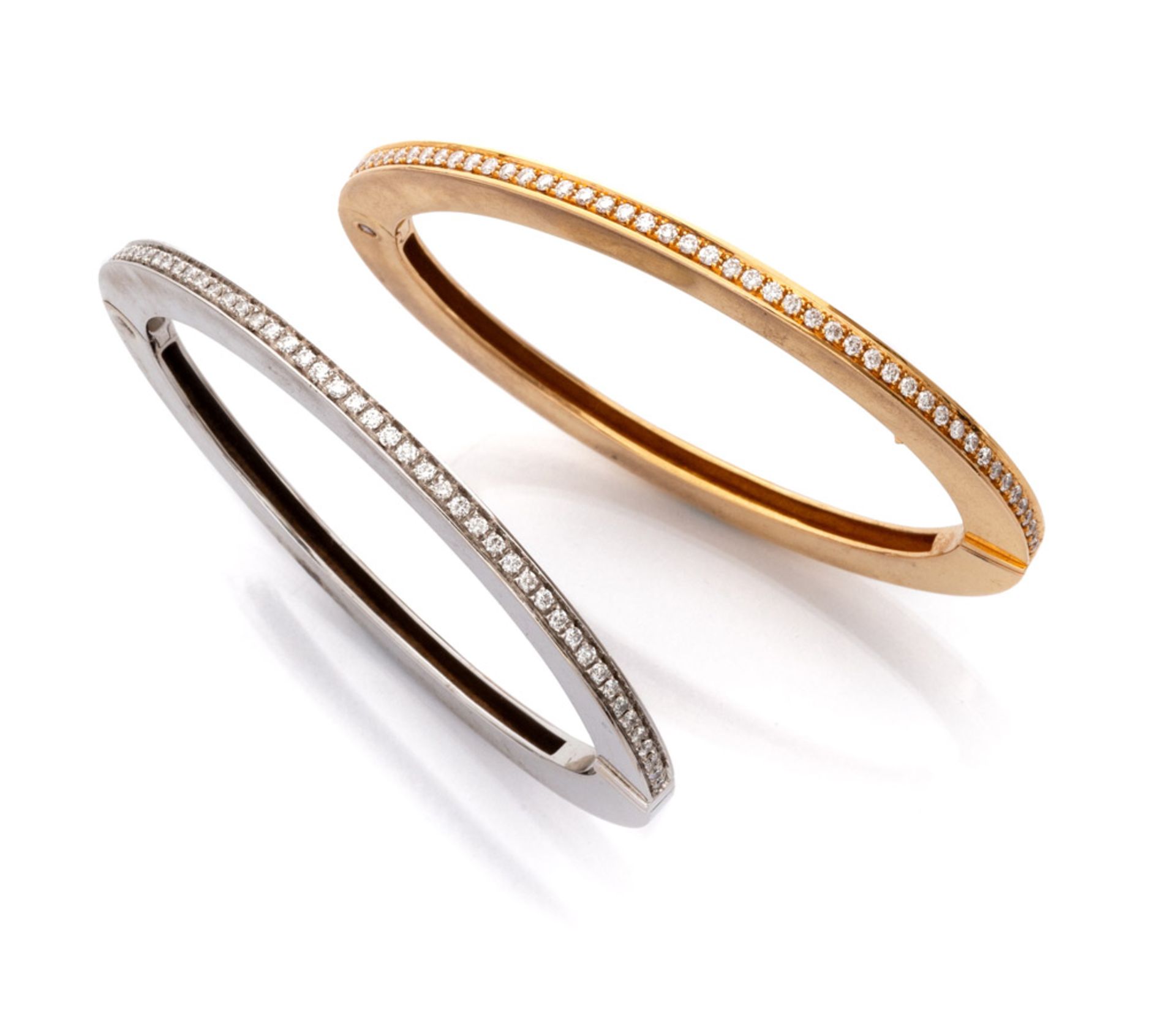 TWO RIGID BRACELETS in white and yellow gold 18 kts., with a line of inset diamonds. Measures cm.