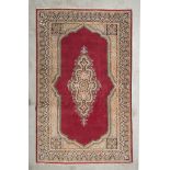 KIRMAN CARPET, MID-20TH CENTURY medallion with branches, in the center field empty on red ground.