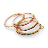 FOUR BANGLES in yellow gold 18 kts., embellished by lines of rubies, sapphires, emeralds and