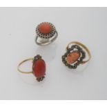 THREE RINGS with mounts in gold and silver with engraved red corals. One with two rose cut side