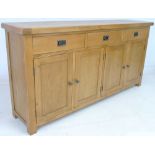 A modern oak sideboard, three drawers over two double cupboards, stile feet,