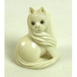 A Japanese ivory netsuke, circa 1900, carved as a cat sitting looking over it's right shoulder,