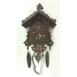 A mid 20th century cuckoo clock, with carved case and cuckoo, the metal weights cast as pine cones.