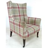 An Edwardian wingback armchair, upholstered in green, cream and red check fabric,