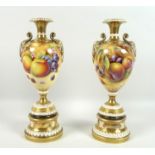 A pair of modern Royal Worcester pedestal vases, foliate clasped twin handles, decorated in a Hand