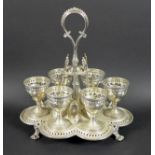 A Victorian silver egg cup stand with six egg cups, raised scroll form handle, all with pierced