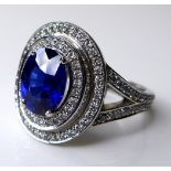 An 18ct white gold, sapphire and diamond dress ring, the dark cornflower blue oval cut stone of