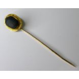 A yellow metal stick pin inset with a ceramic scarab beetle, tests as 22ct gold, 8cm long, 3.8g,