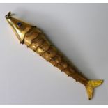 A gold articulated fish with blue spinel eyes, unmarked but tests up to 14ct gold, 7.5cm long, 4.7g.