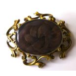 A Victorian yellow metal mourning brooch, with scrolling frame around a glazed oval window set