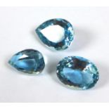 A group of three large loose cut blue topaz gem stones, comprising two pear cut stones, 22.47 by