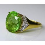 An 18ct gold green tourmaline and diamond ring, the central lime green oval cut tourmaline approx