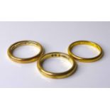 A group of three gold wedding bands, two 9ct gold, sizes L/M, 5.7g combined, and one yellow metal