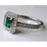 An 18ct white gold, emerald and diamond dress ring, the central emerald cut stone of approximately