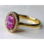 An 18ct rose gold, pink sapphire and diamond dress ring, the central oval cut deep rose pink stone