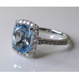 An 18ct white gold, aquamarine and diamond ring, the central cushion cut aquamarine of approximately