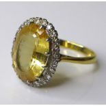 An 18ct gold and yellow topaz dress ring, the oval cut central stone of 12 by 8mm and surrounded