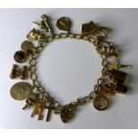 A 9ct gold charm bracelet with heart padlock clasp, with seventeen 9ct gold charms including a