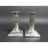 A pair of late Victorian silver dwarf candlesticks, of Roman Doric column form, with square plinths,