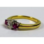 An 18ct gold, diamond and ruby three stone ring, the central oval cut diamond of 4.47 by 3.2mm and