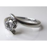 A platinum and diamond solitaire ring of contemporary swirl design, diamond of approximately 0.