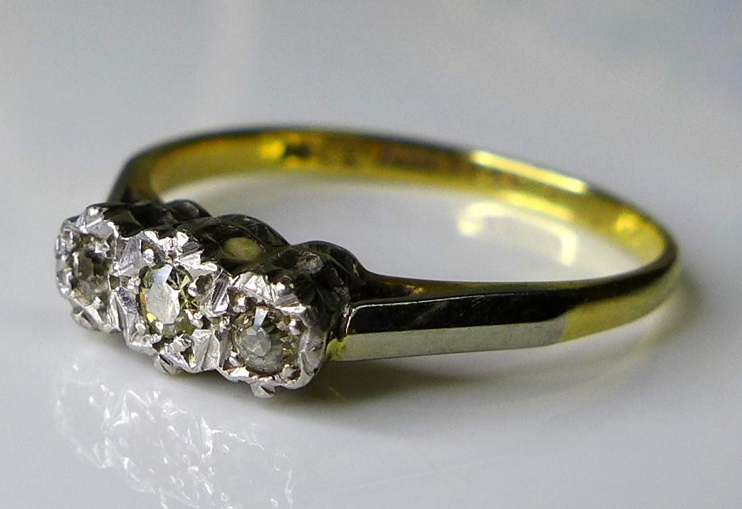 An 18ct gold and platinum three stone diamond ring, illusion set, central stone 0.1ct, size N, 2.3g.