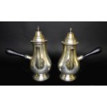 A pair of George V silver chocolate pots, of bellied form with side spouts, turned ebonised
