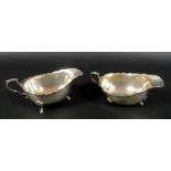 A pair of George VI silver sauce boats, each raised on three hoof feet and with C scroll handles,