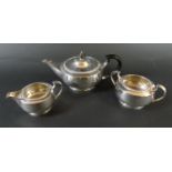 A George V three piece silver tea set, comprising of squat form teapot with ebonised handle and