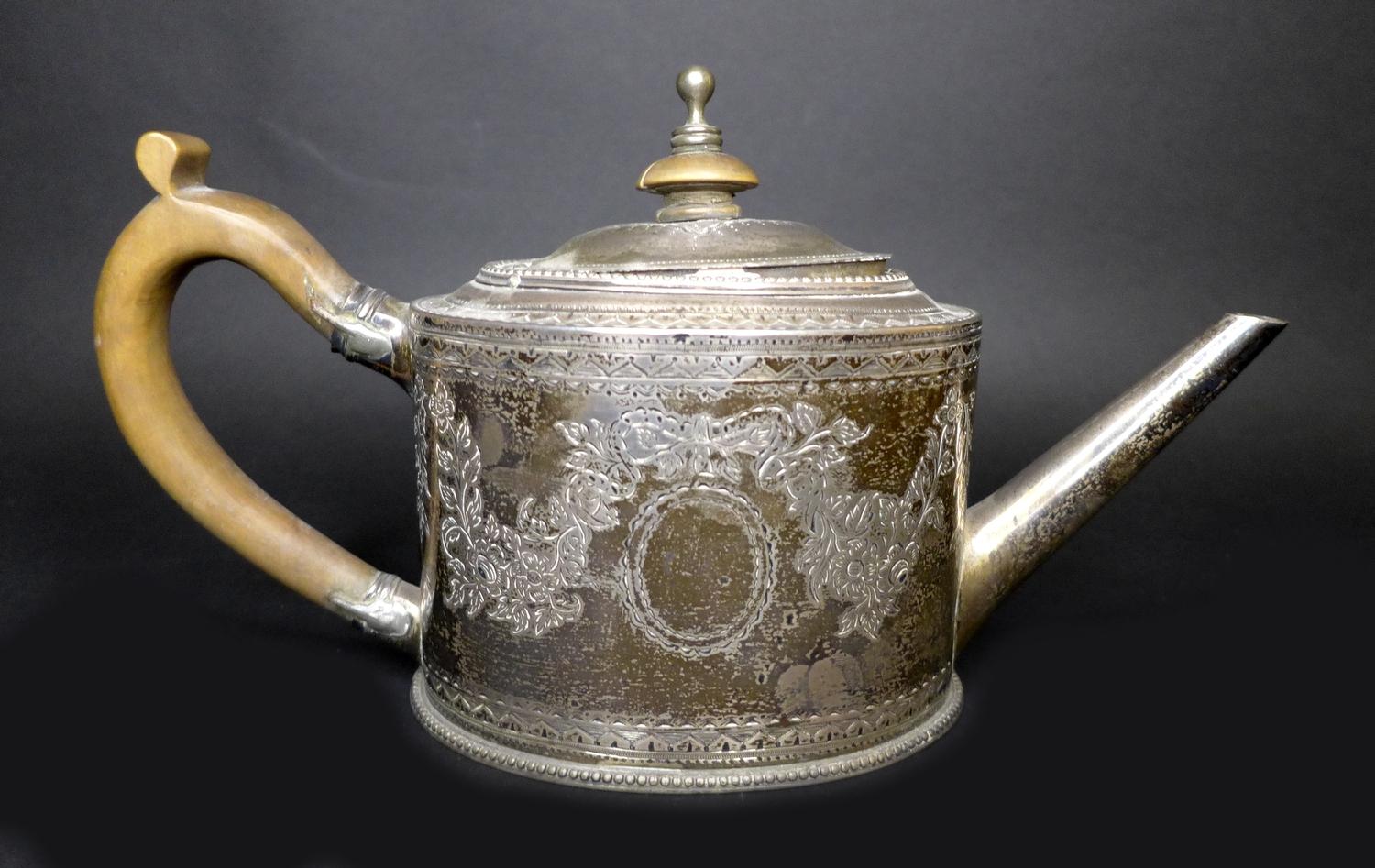 A George III silver teapot, decorated in Neoclassical taste with engraved swags and scrolls,