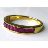An 18ct gold and ruby half eternity ring, set with eleven square cut rubies, each stone