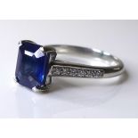 A platinum, sapphire and diamond ring, the emerald cut deep cornflower blue sapphire of