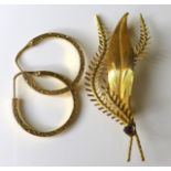 An 18ct gold brooch, modelled as a leaf with intertwining fern fronds, set with a garnet, 4.4g,