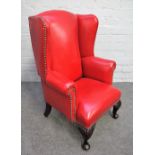 A diminutive rouge leather upholstered wingback armchair, on squat cabriole supports,