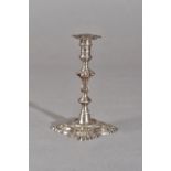 A George II silver taper stick, of cast form with a shaped stem, raised on a shaped square base,