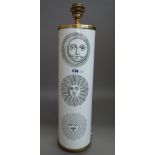A Fornasetti table lamp decorated with sun motifs against a cylindrical white metal and gilt body,